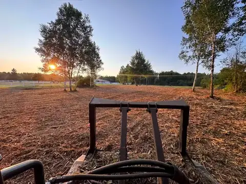 Mulched pasture at sunset beside a white fence